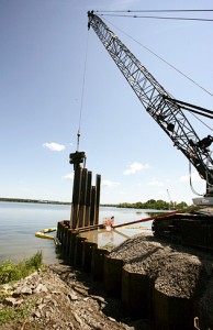 A vibratory hammer is used to push the steel panels down into the lake's bottomThe hammer creates a vibration, allowing the sheet to slide easily into place. 